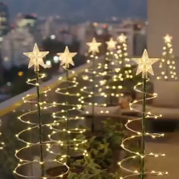 Árboles espirales con estrella encendidos al anochecer en una terraza
