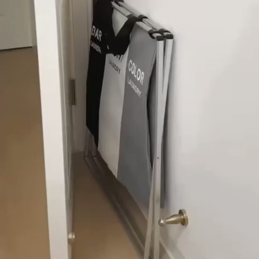 Cesto separador de ropa plegado y guardado detrás de una puerta