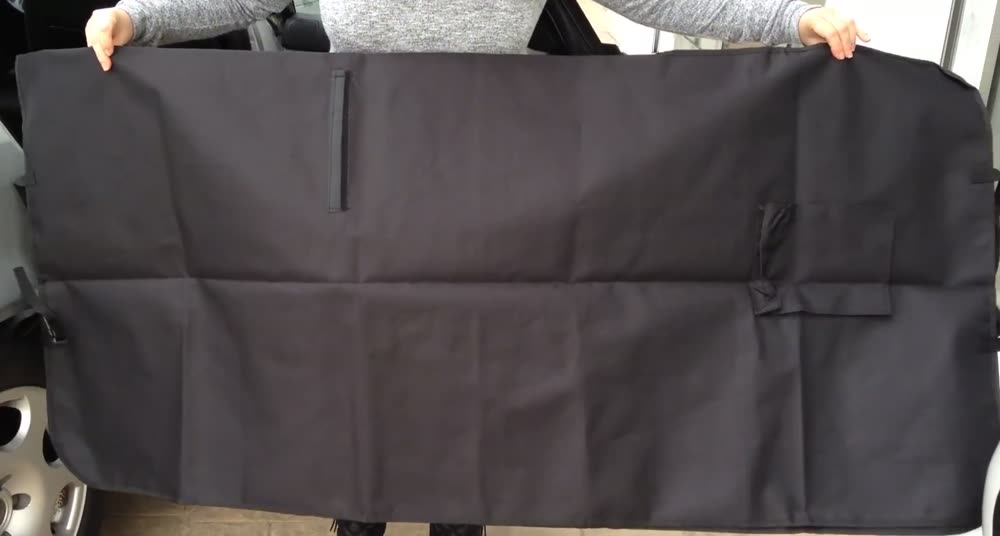Lo que recibes: un cubre asiento negro para mascotas, extendido y sostenido con las dos manos