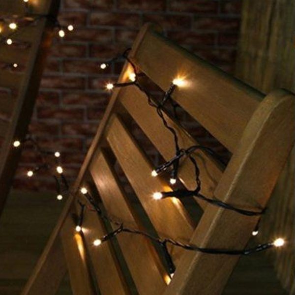 Tira de cable verde con luz cálida repartida en el respaldo de una silla de jardín