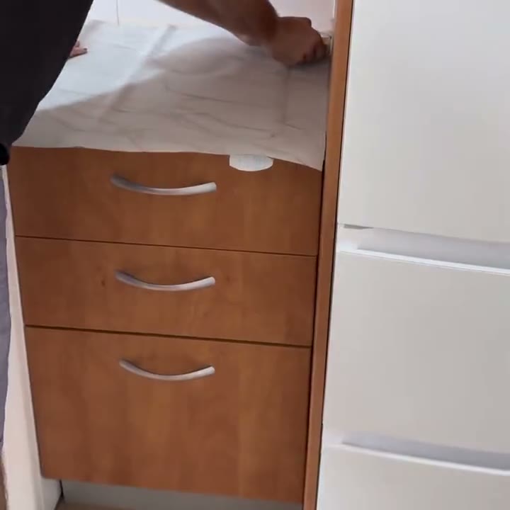 Manos alisando el papel adhesivo sobre el mesón