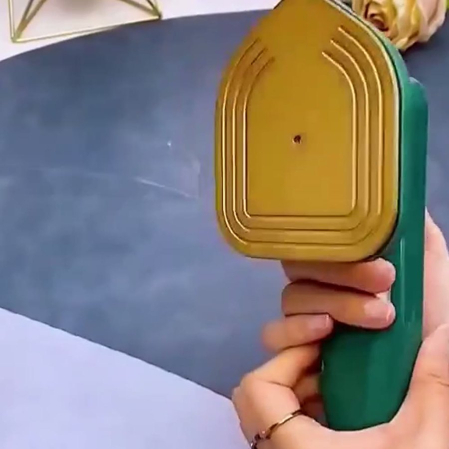 Mini plancha verde vista por la placa dorada con relieve, que es la parte que se apoya sobre la tela