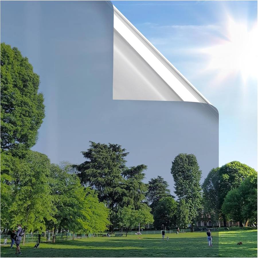 Una esquina de la lámina plateada despegándose de un vidrio y reflejando árboles y cielo